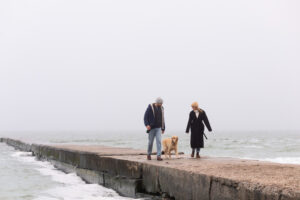 Man en vrouw zijn met hun hond aan het lopen bij de zee. Ze zijn begonnen met hun goede voornemens